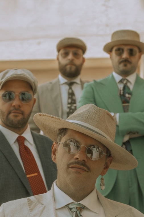 I quattro musicisti in posa, con occhiali da sole e cappelli