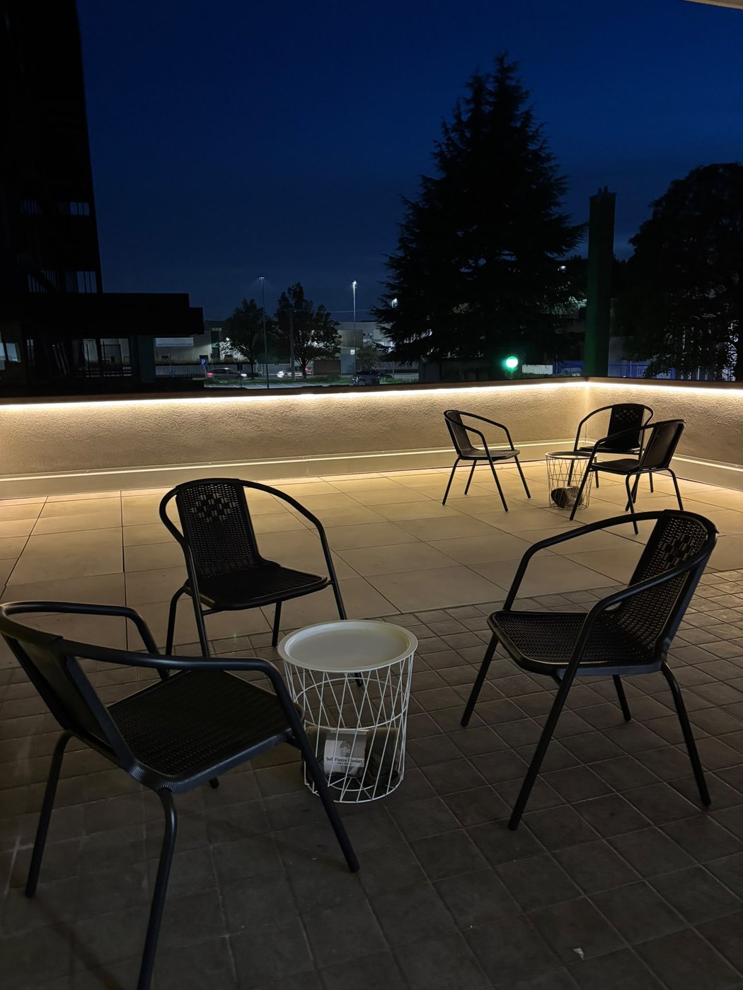 The FLAC Concorezzo terrace at sunset: metal seating, small tables and warm lights set into the railing